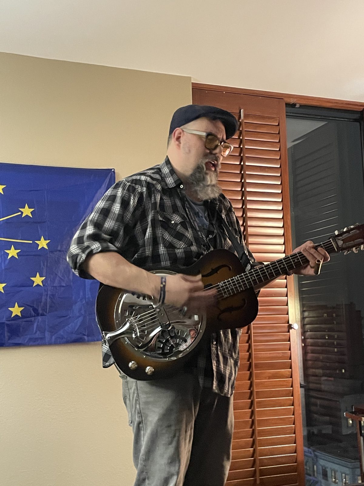 A musician playing resonator guitar in front of the Indiana flag