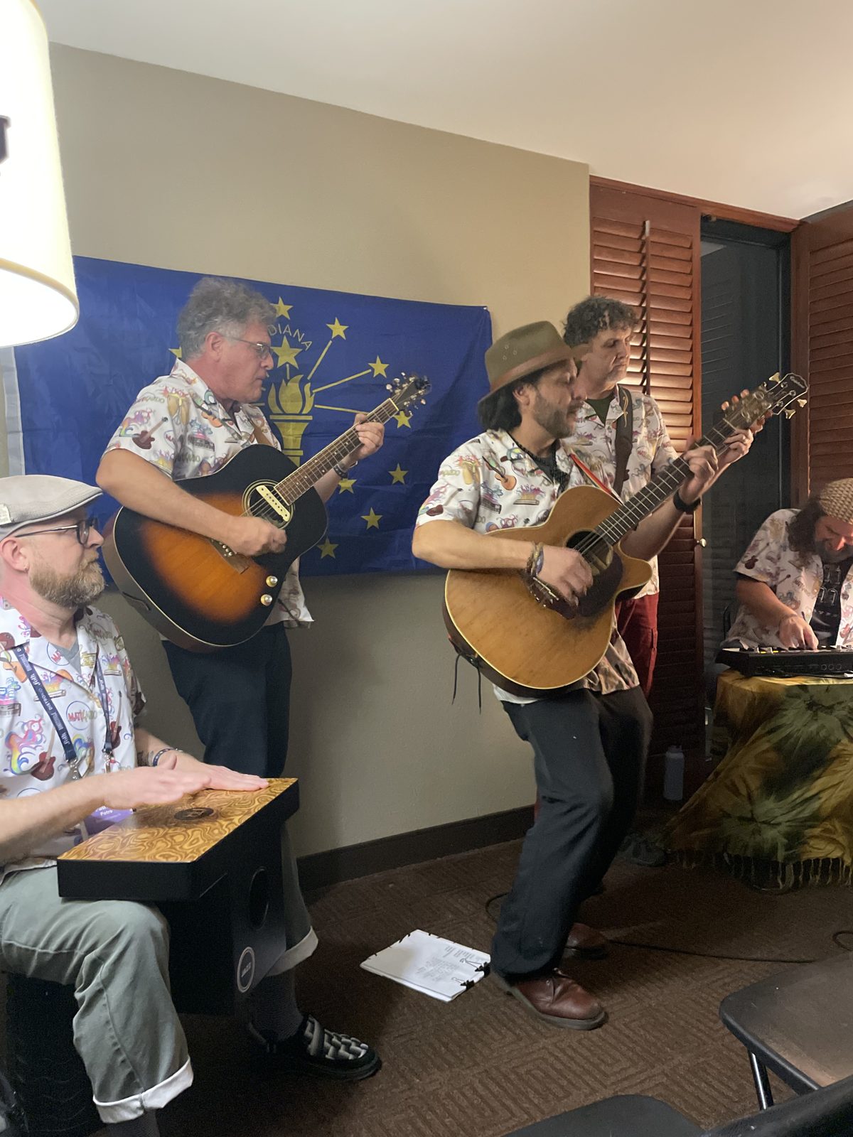 Two musicians in floral shirts performing in front of the Indiana flag