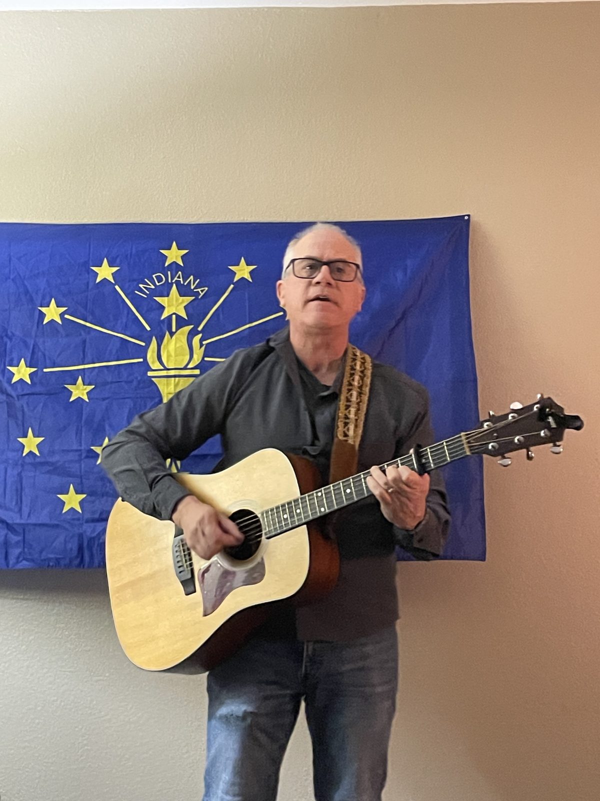 A guitarist performing in front of the Indiana flag