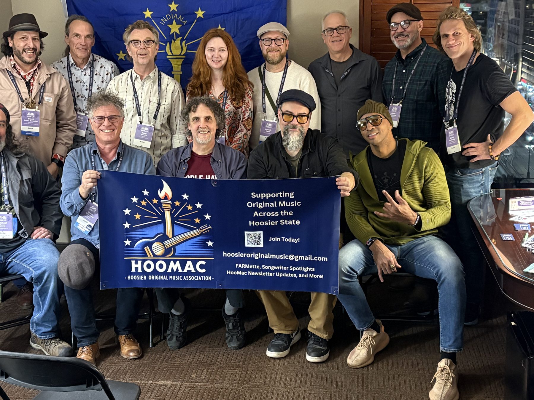 HooMac showcase artists gathered around the HooMac banner in front of the Indiana flag at Folk Alliance International