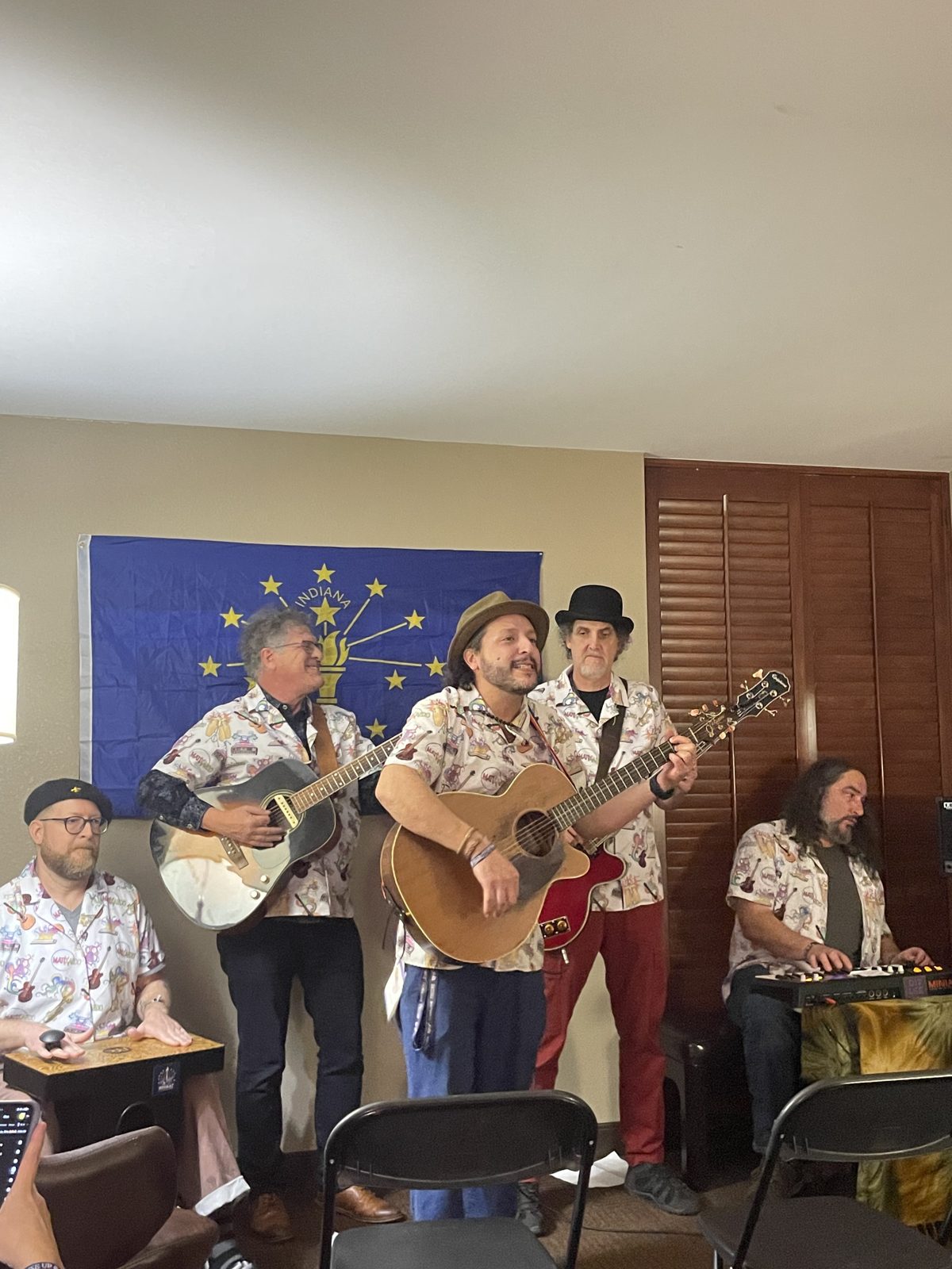 A trio in matching floral shirts performing under the Indiana flag