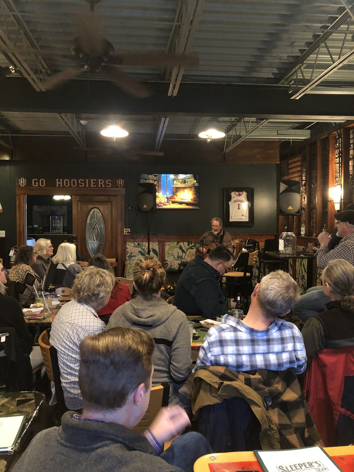 A full room at Sleeper's listening to a songwriter under the Go Hoosiers sign